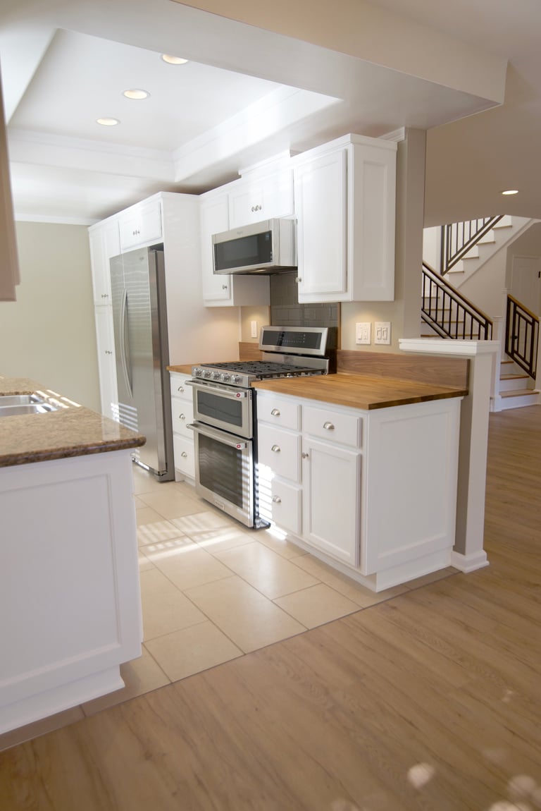 Modern kitchen with white cabinets, stainless steel appliances, wooden countertops, and open floor plan layout