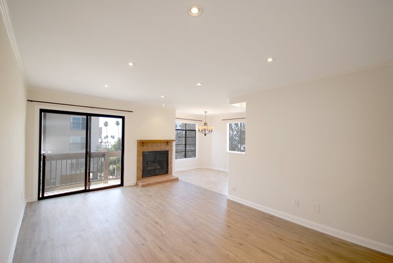 Bright modern living room with wood flooring, fireplace, sliding glass doors, recessed lighting, and cream-colored walls