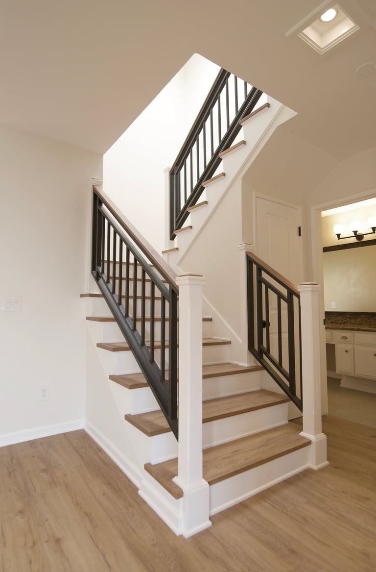 Modern staircase with white walls, wooden steps, and black metal railings in a bright home interior